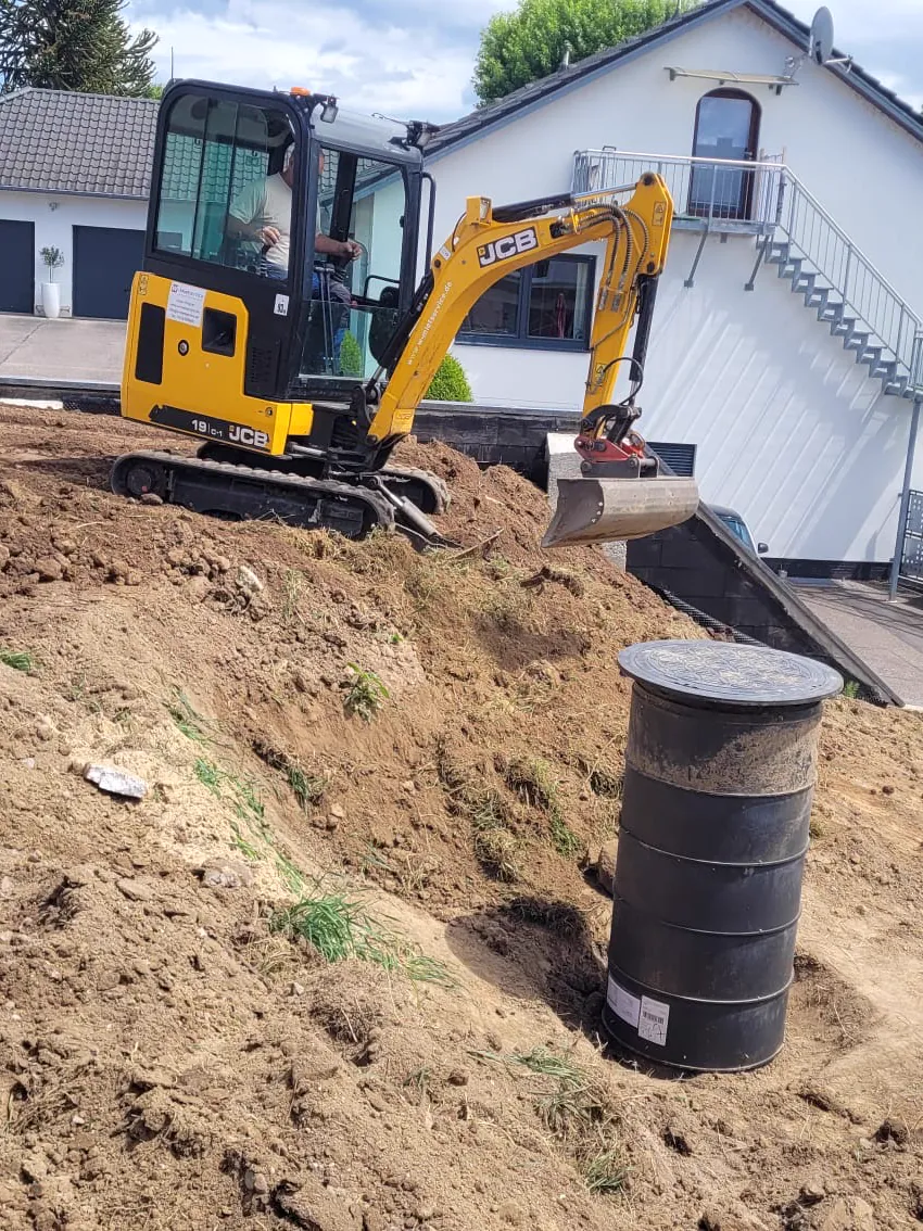 Minibagger beim Aushub vor einem Haus