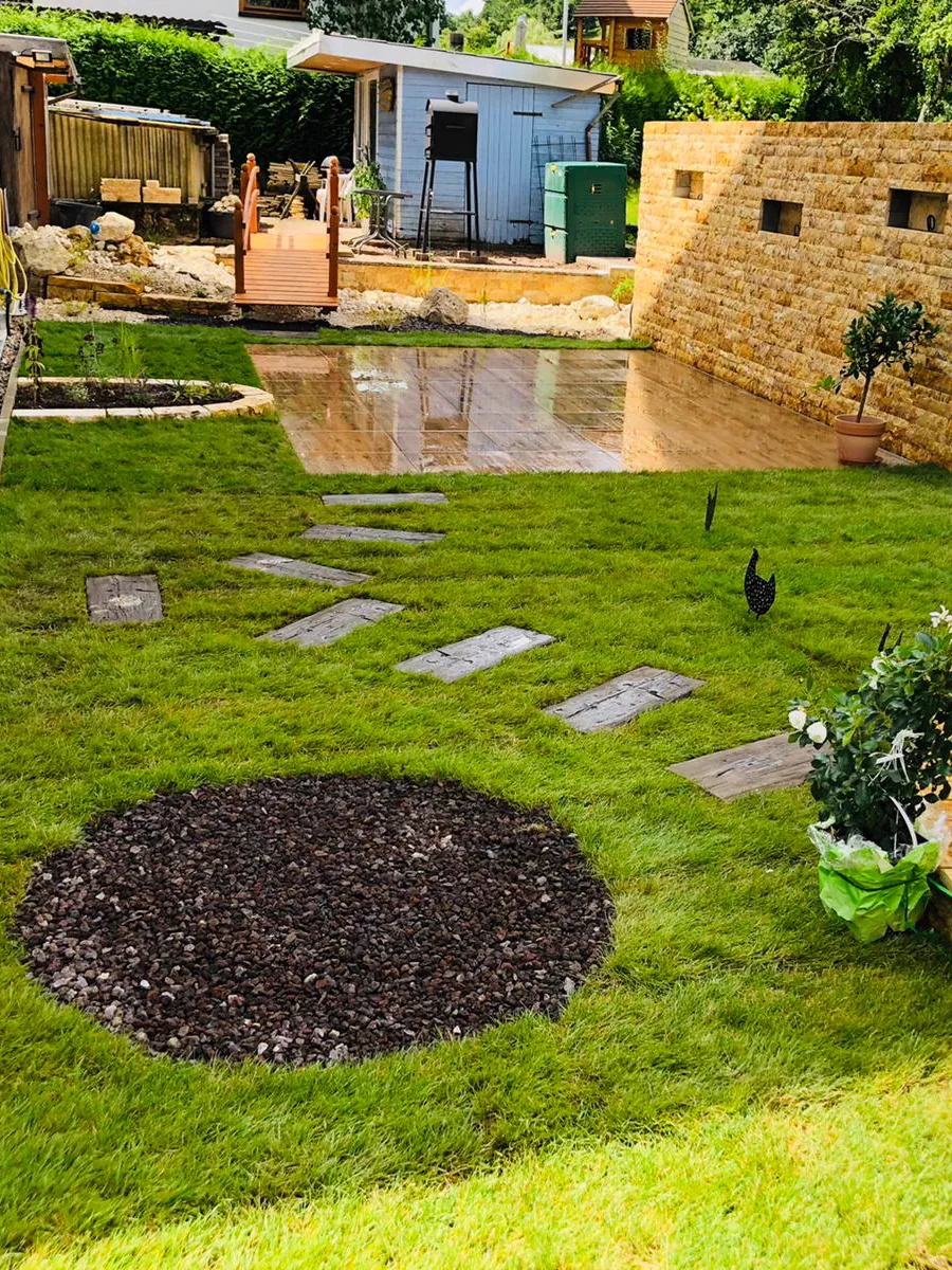 Garten mit Rasen, Trittplatten und rundem Beet