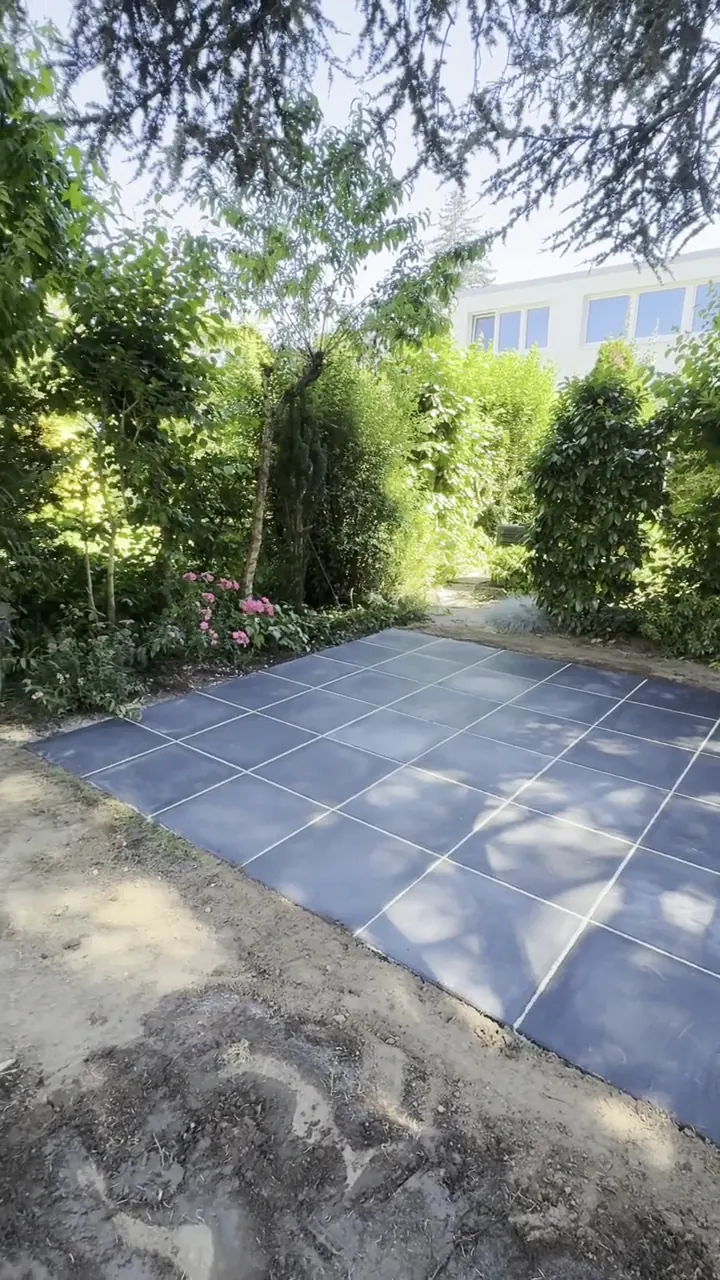 Fertige Terrasse aus dunklen Platten im Garten